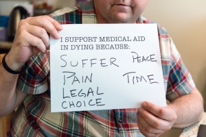 Matt Fairchild holds a sign showing why he supports medical aid in dying.  The 46-year-old Burbank resident wants to have the right to die if the pain from his melanoma becomes unbearable. (Heidi de Marco/KHN)