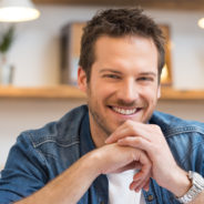 Closeup of smiling young businessman looking at camera in office