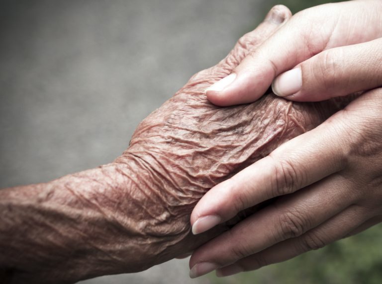 Senior and young holding hands