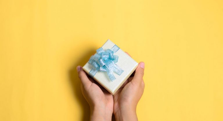 Cropped Hands Of Woman Holding Gift Box Over Yellow Background