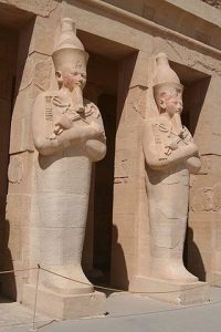 These statues of Hatshepsut at her tomb show her holding the crook and flail associated with Osiris.