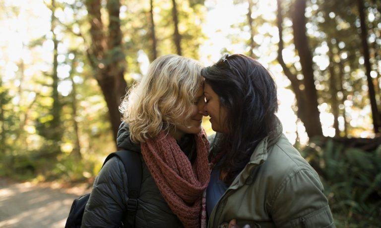 Tender, affectionate lesbian couple hiking in woods