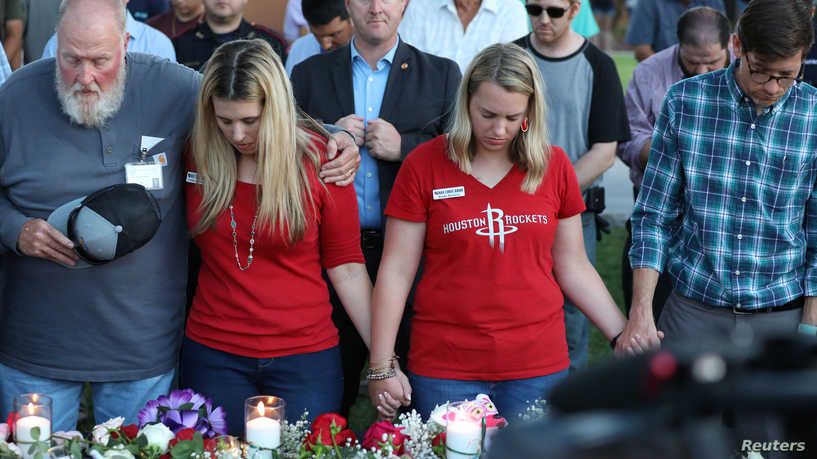 Mourners bow their heads in prayer during a vigil held after a shooting left several people dead at Santa Fe High School in Santa Fe, Texas