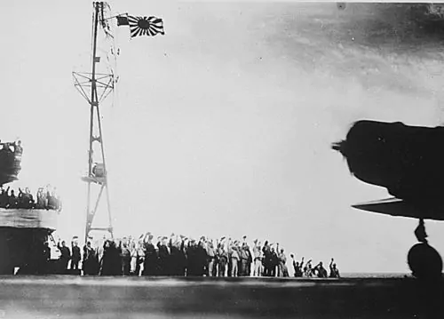 In this captured photograph, Japanese sailors wave their caps as the planes that will soon raid Pearl Harbor leave their carriers