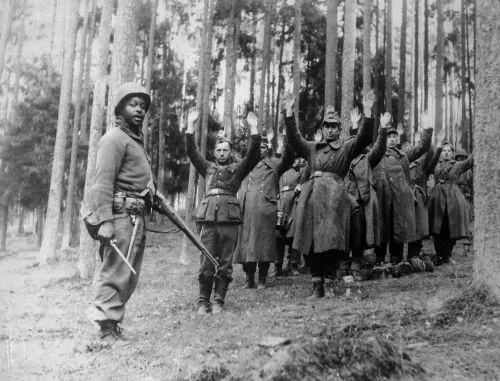 12th Armored Division soldier with German prisoners of war, April 1945