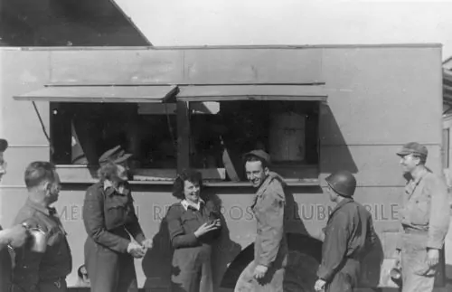 Liz Richardson (left) and Mary Haynsworth with smiling GIs in front of their Clubmobile in Normandy