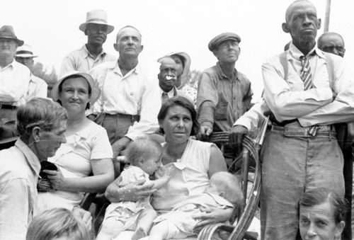 Men, women, and children, black and white, listen to a speaker at an outdoor Southern Tenant Farmers Union meeting, 1937.