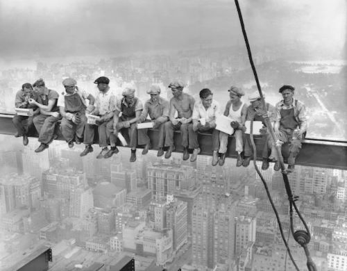 Workers atop the 70-story RCA building in New York's Rockefeller Center lunch on a steel beam overlooking the city in 1932.