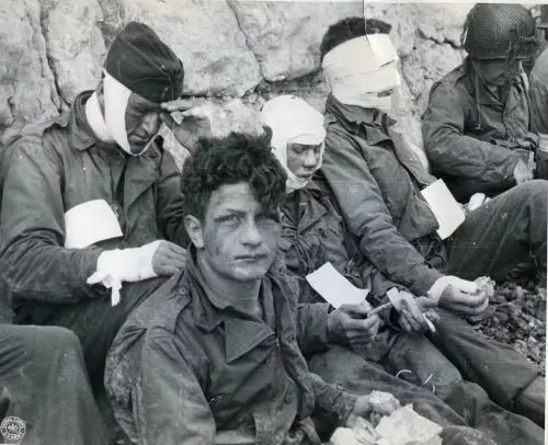 Wounded members of the 16th Infantry Regiment wait for evacuation from the beach on D-Day