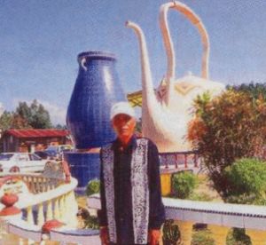Ayah Pin standing in front of the large teapot and the vase in the Sky Kingdom compound prior to its demolition