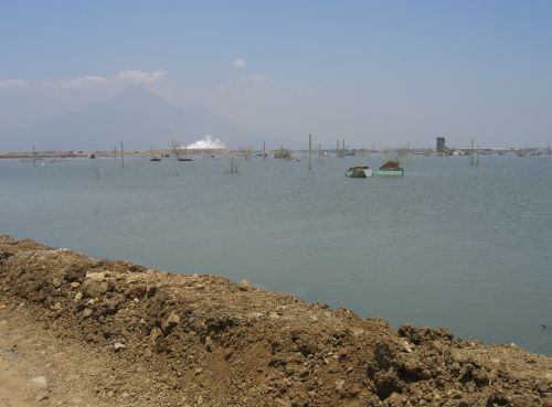 Lake created by mud in Sidoarjo, with steaming mudflow in background