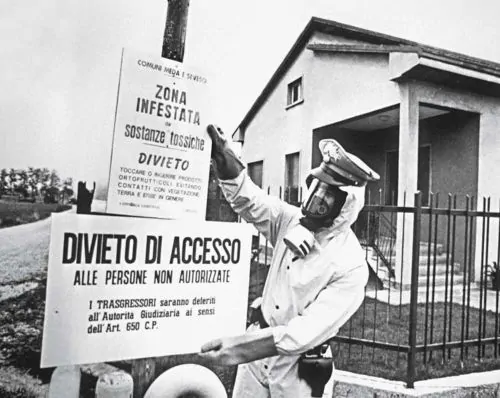 A Carabiniere in a biohazard suit installs signs warning of the presence of toxic chemicals in  Seveso